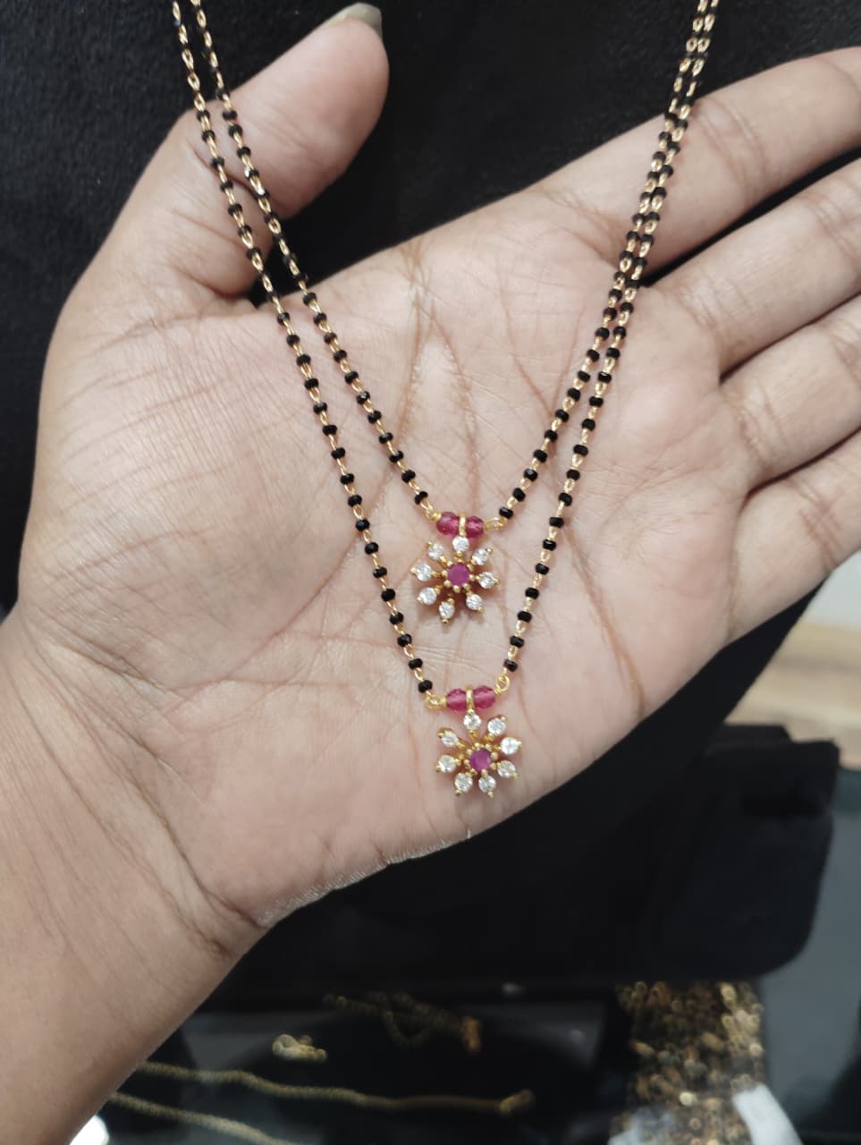 double-layer black beaded mangalsutra with two pink floral pendants and clear petal stones