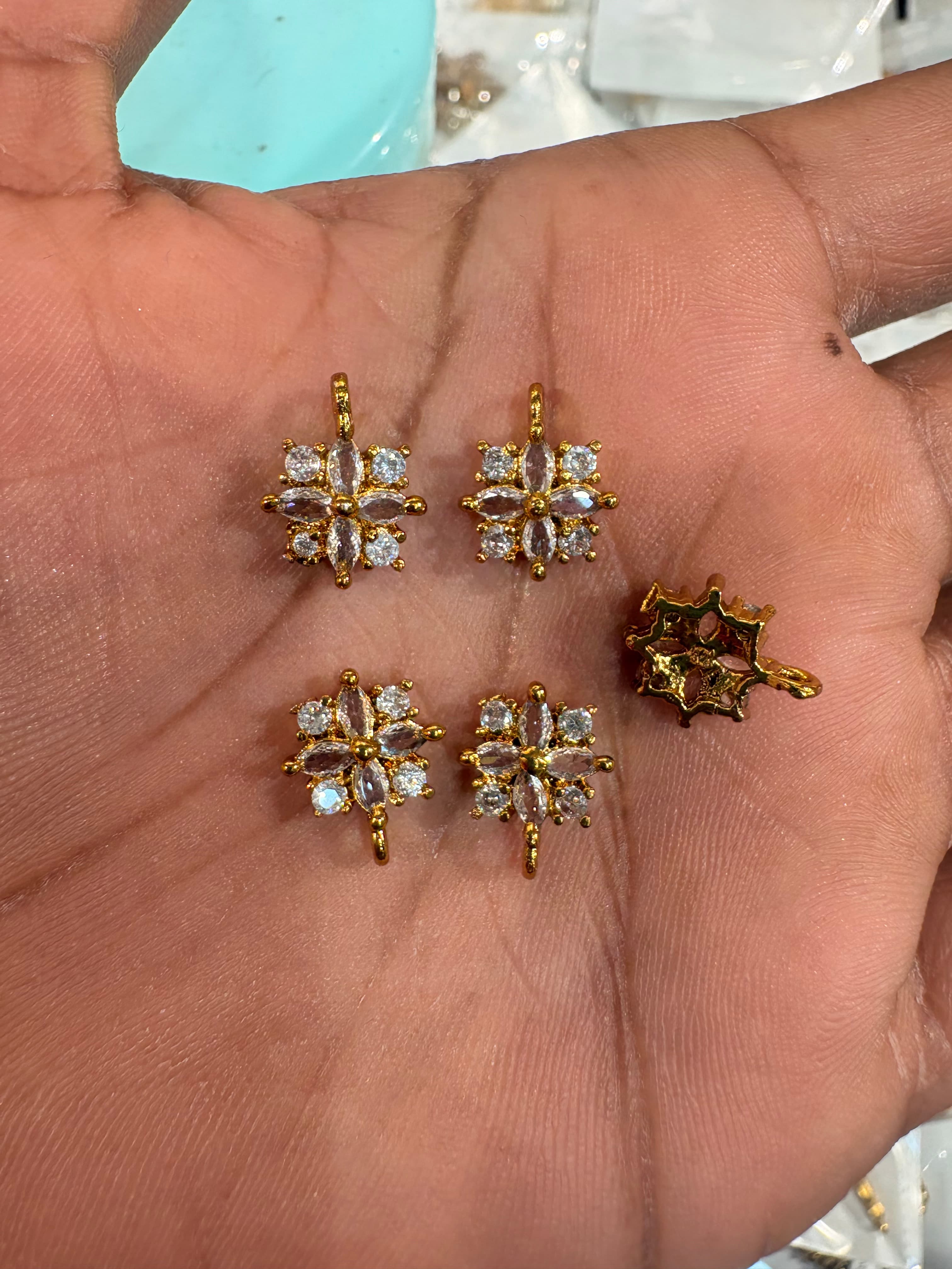 gold-tone floral charm bits with round and marquise clear accents held on a palm