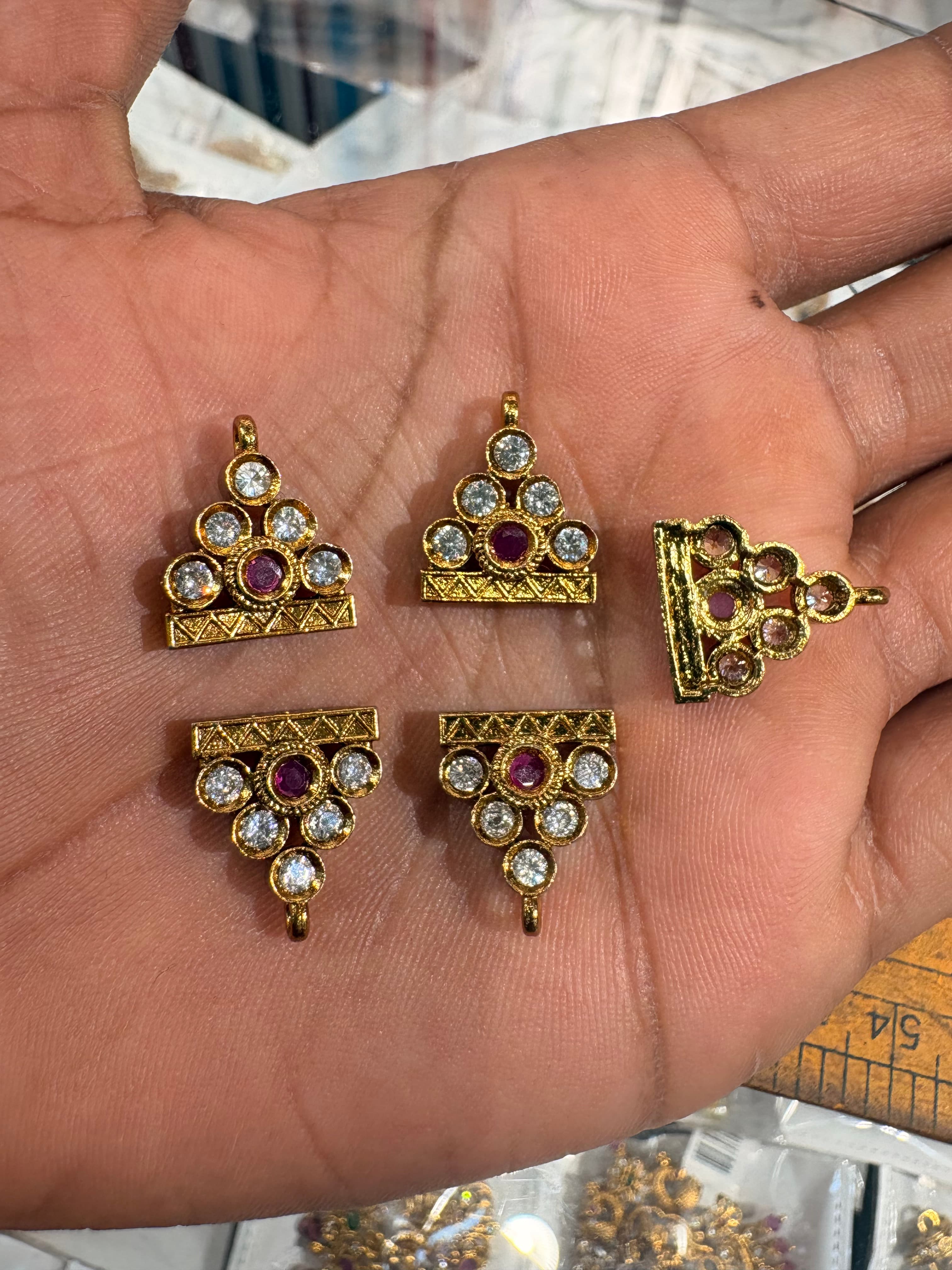 Small gold-tone triangular pendant bits with clear round accents and a central pink round accent