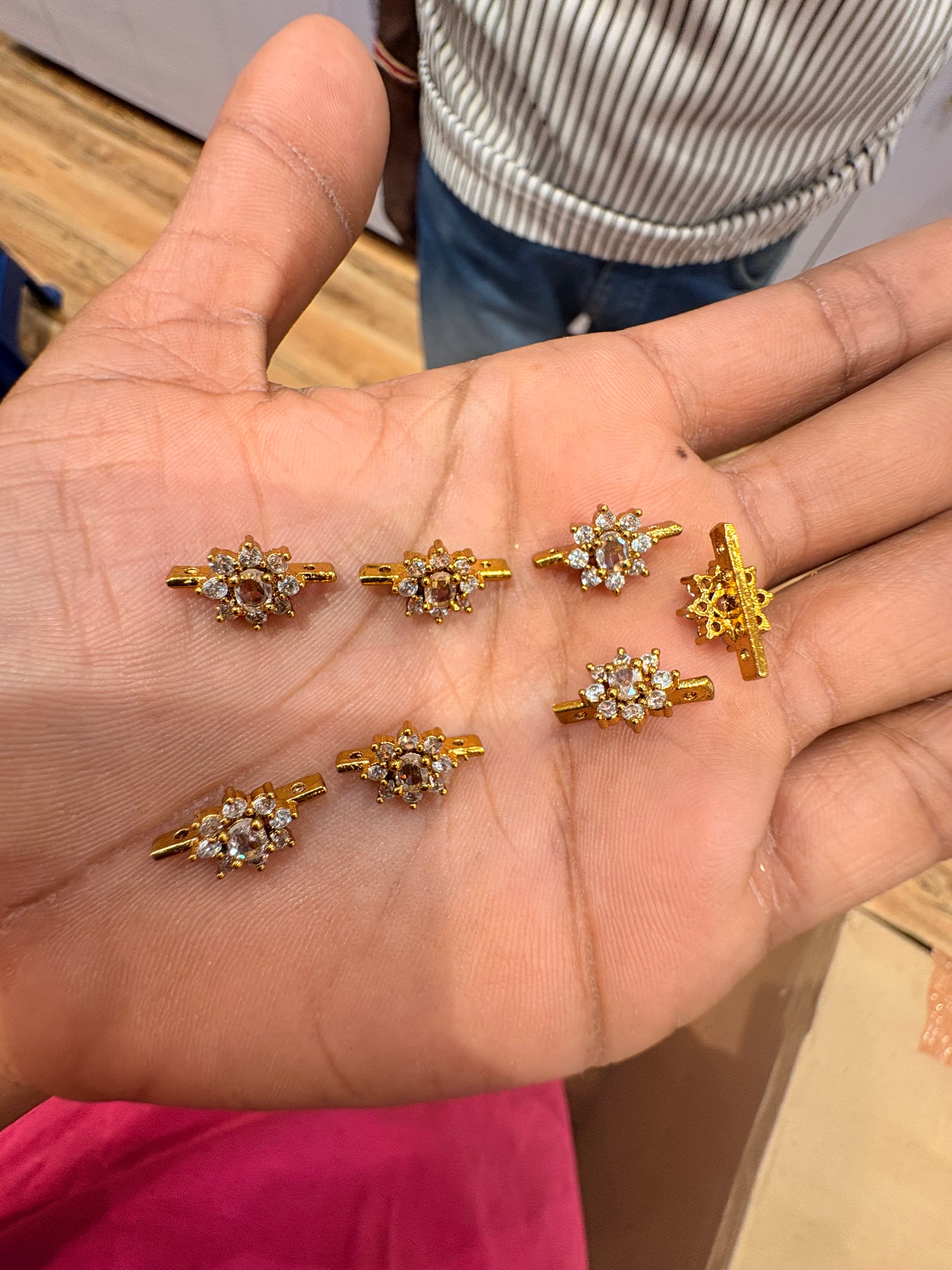 Small gold-colour floral connector bits with clear round accents on a horizontal bar
