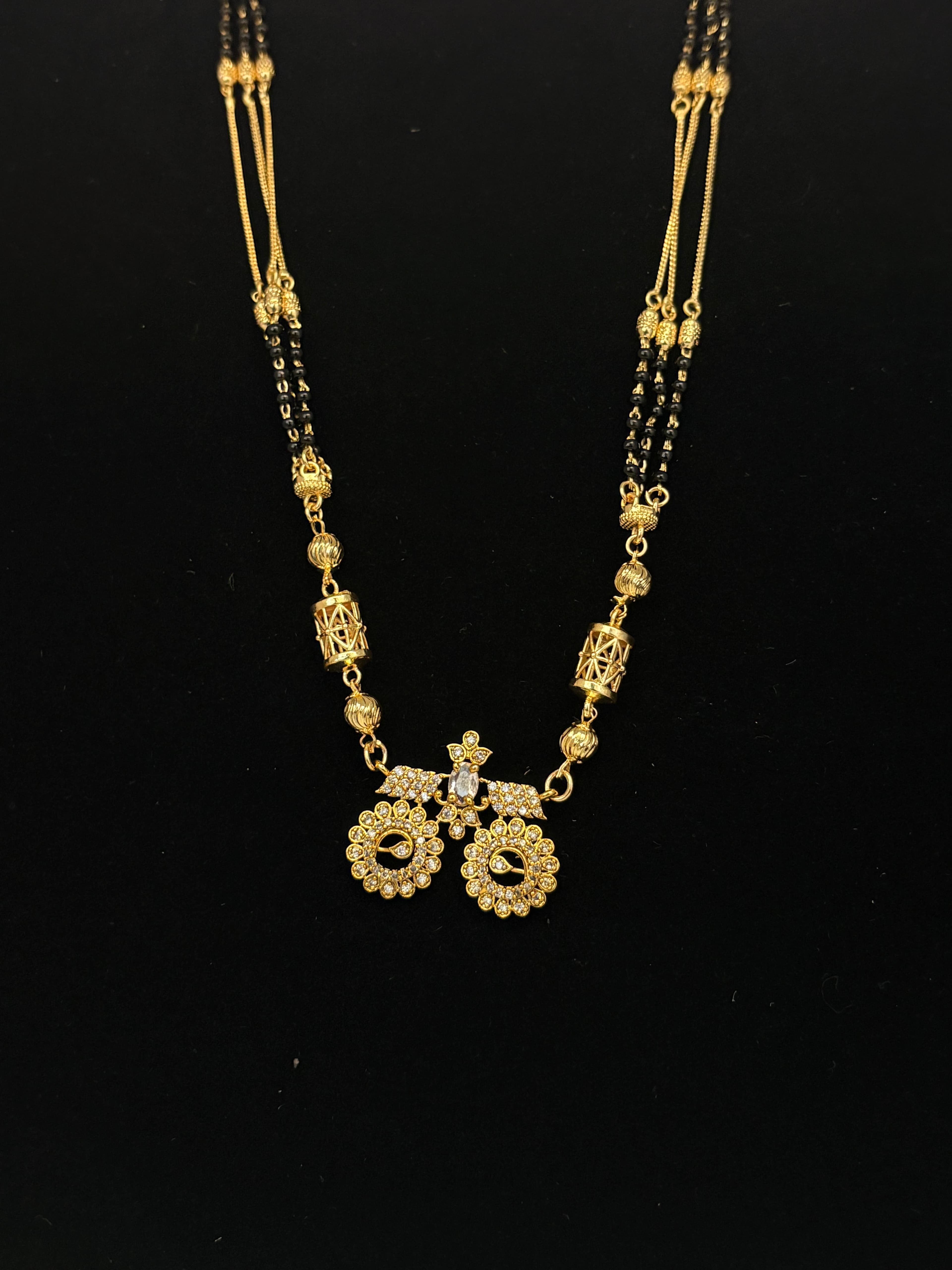 Gold-tone mangalsutra with double black bead strands and a floral pendant with clear accents