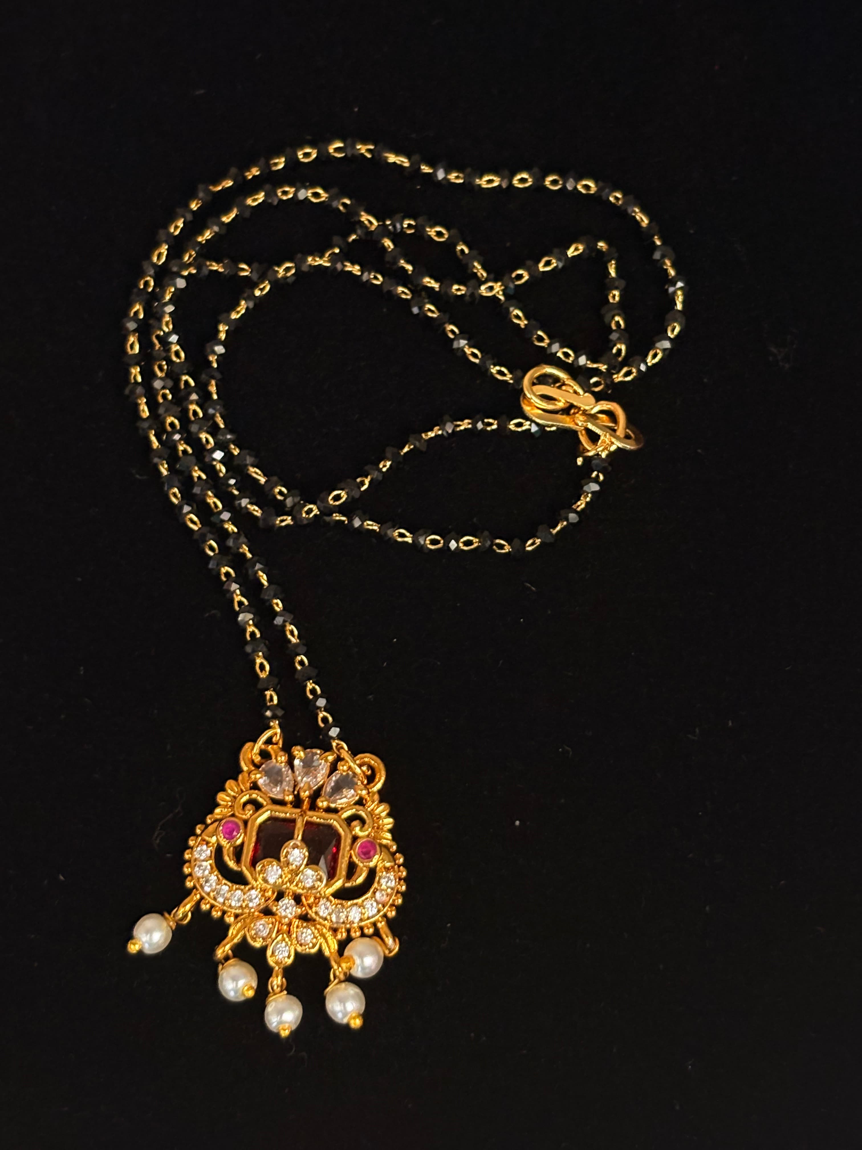 Double black-bead mangalsutra chain with gold-colour floral pendant and three pearl drops