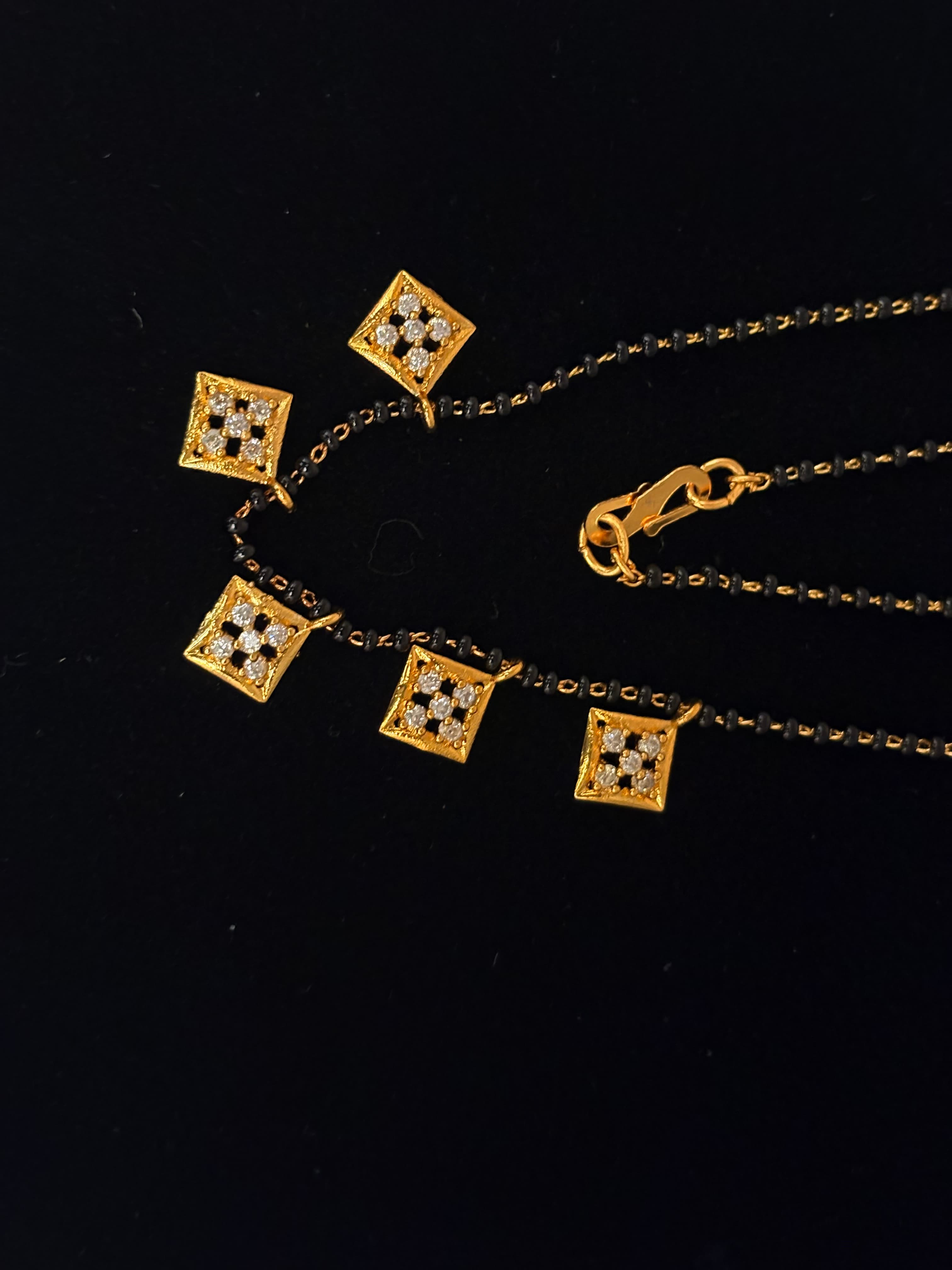 Gold-tone mangalsutra chain with black beads and square pendants set with clear round accents