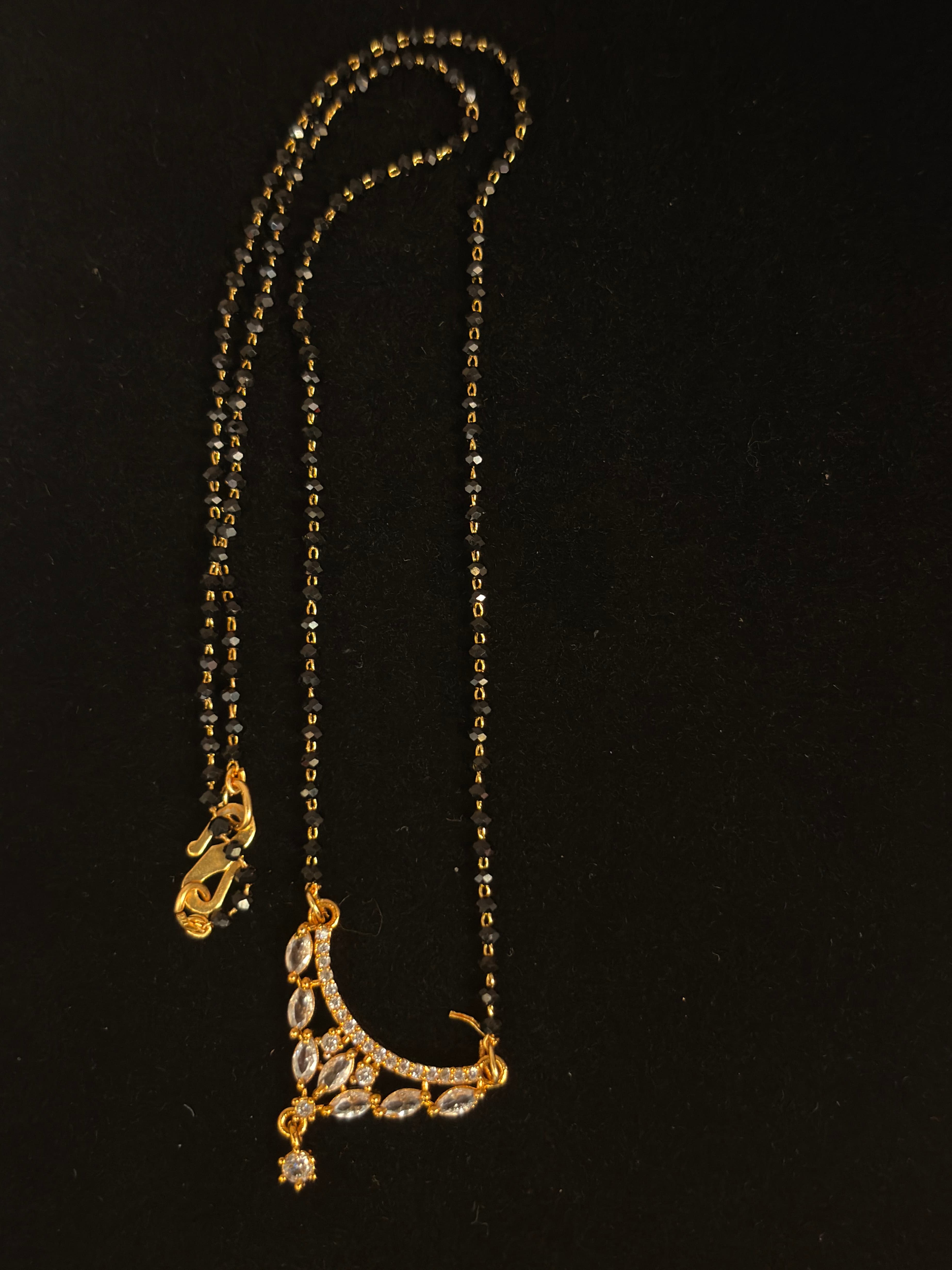 Twin-strand black-bead mangalsutra with gold-tone crescent pendant and dangling charm