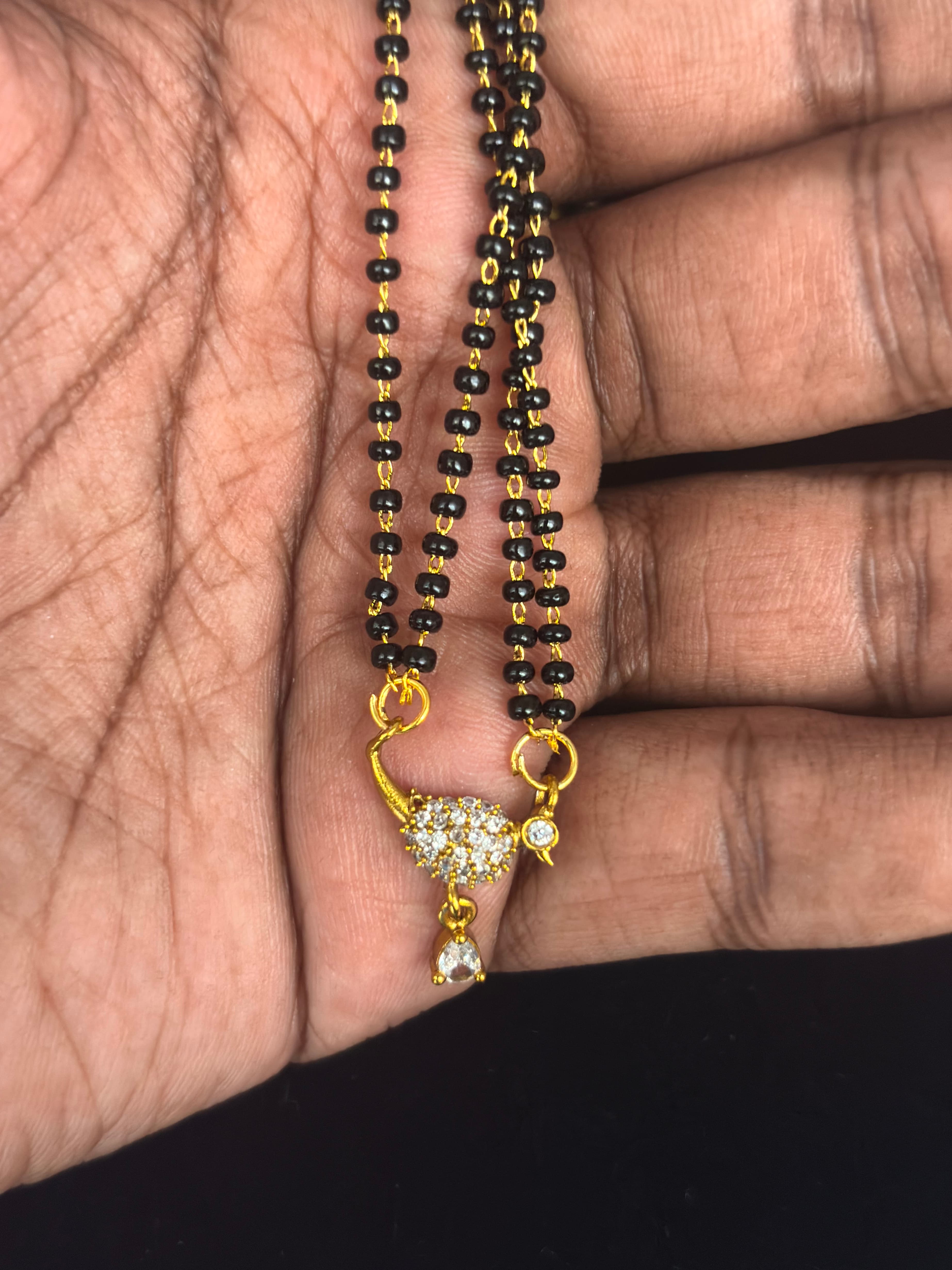 Double-strand black bead mangalsutra with gold-coloured links and small teardrop-accent pendant