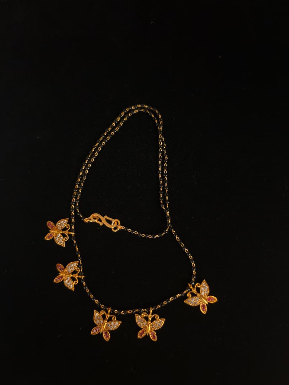 Black-bead mangalsutra chain with five gold-tone butterfly charms with clear and pink accents
