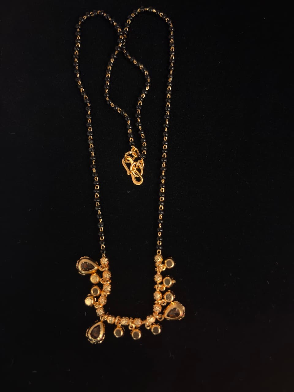 Black-beaded mangalsutra with two-strand chain and gold-tone teardrop and round accents