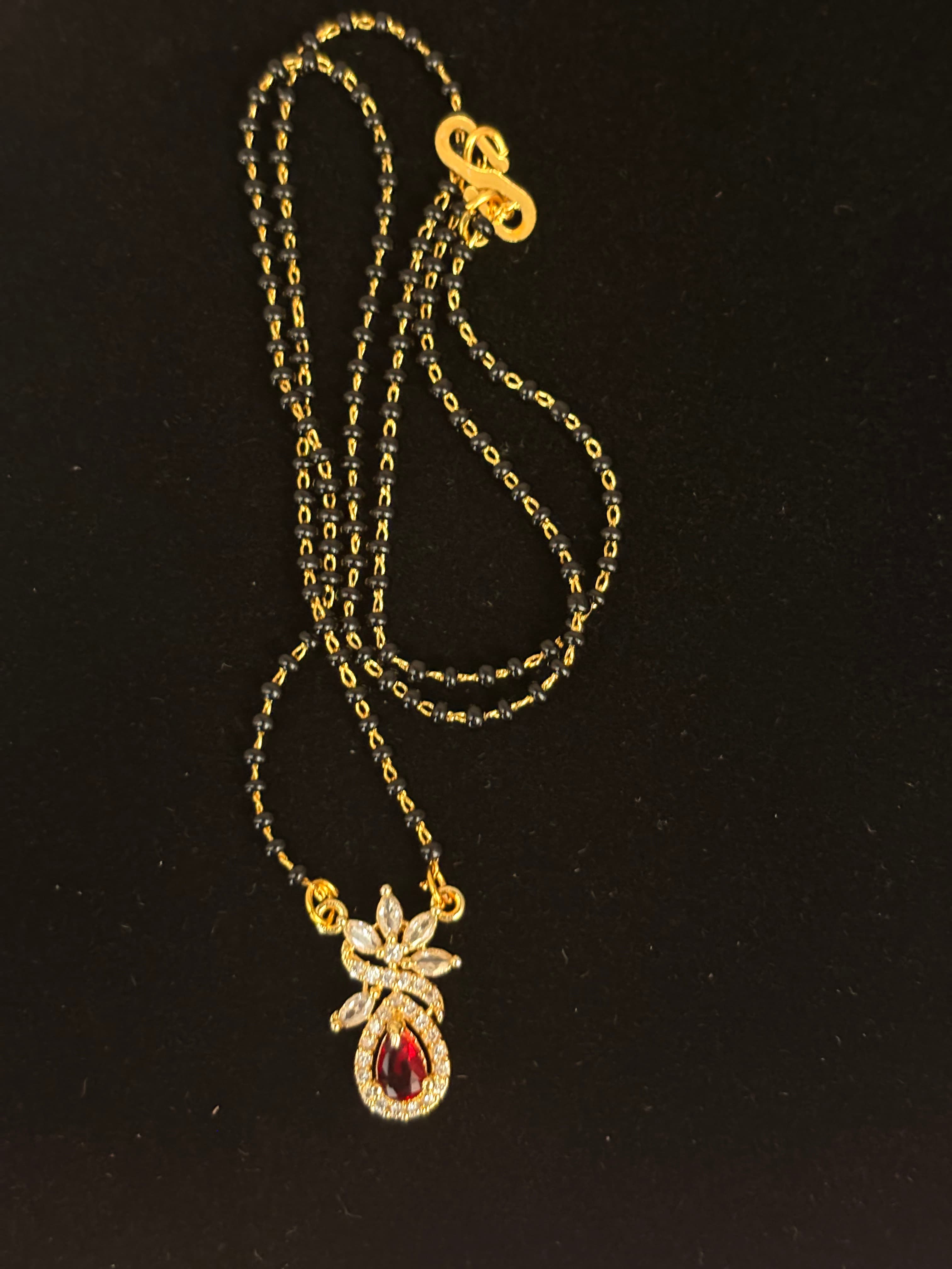 Double-strand black bead mangalsutra with a gold-tone chain and red teardrop pendant