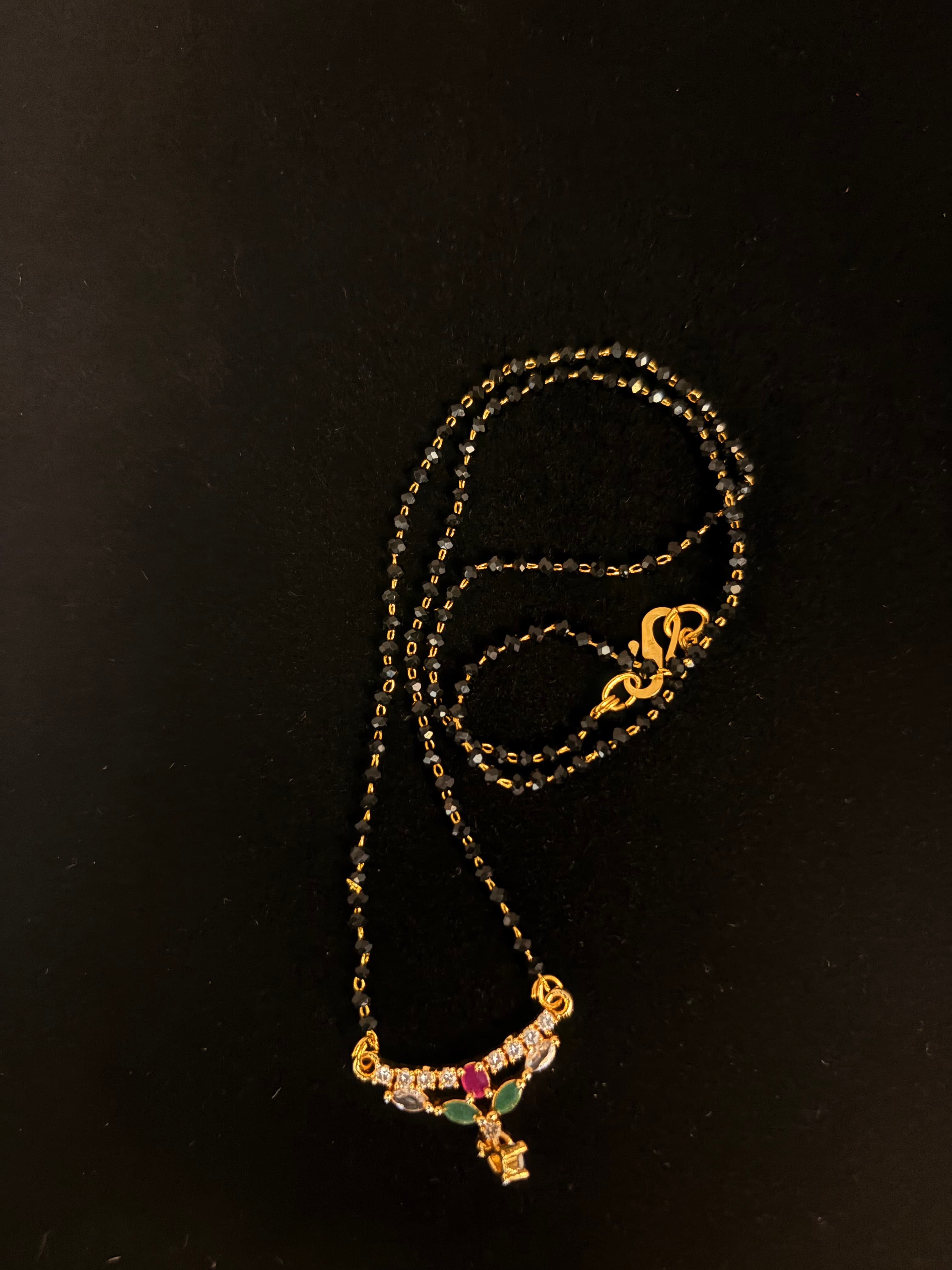 Twin-strand black-bead mangalsutra with small gold-tone pendant and coloured accents