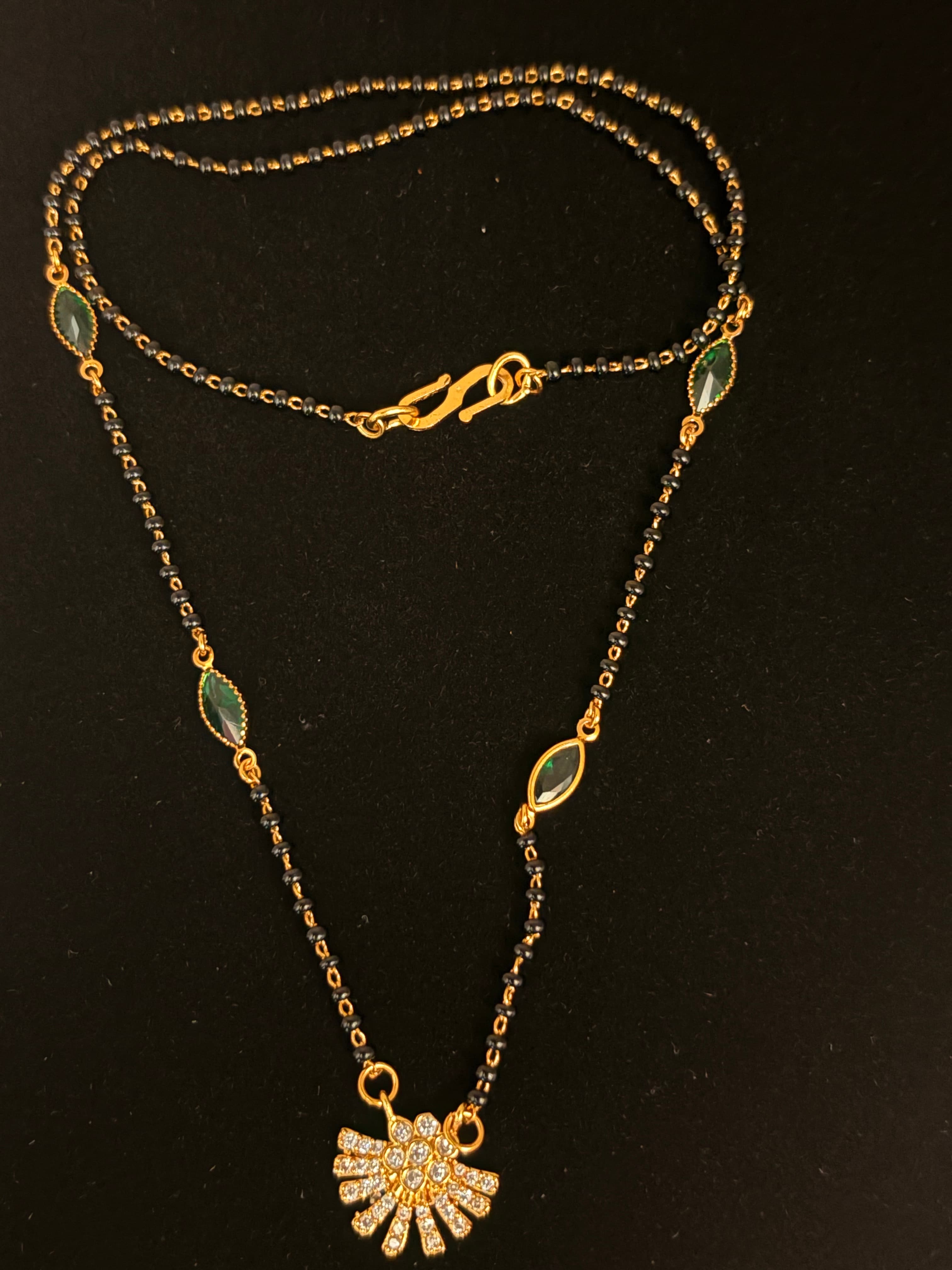 Black-beaded mangalsutra chain with green marquise accents and gold-tone pendant