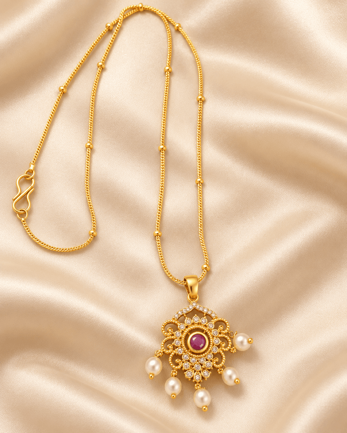 Gold-tone chain with ornate pendant, red centre accent, clear details and five dangling white beads