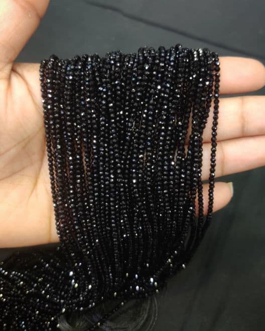 Multiple strands of small round faceted black beads with glossy sparkle