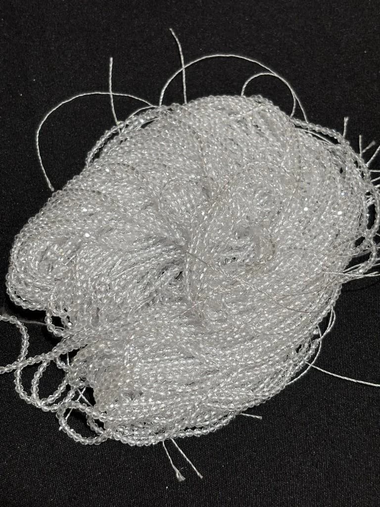 Coiled single strand of translucent white faceted hydro beads on black background