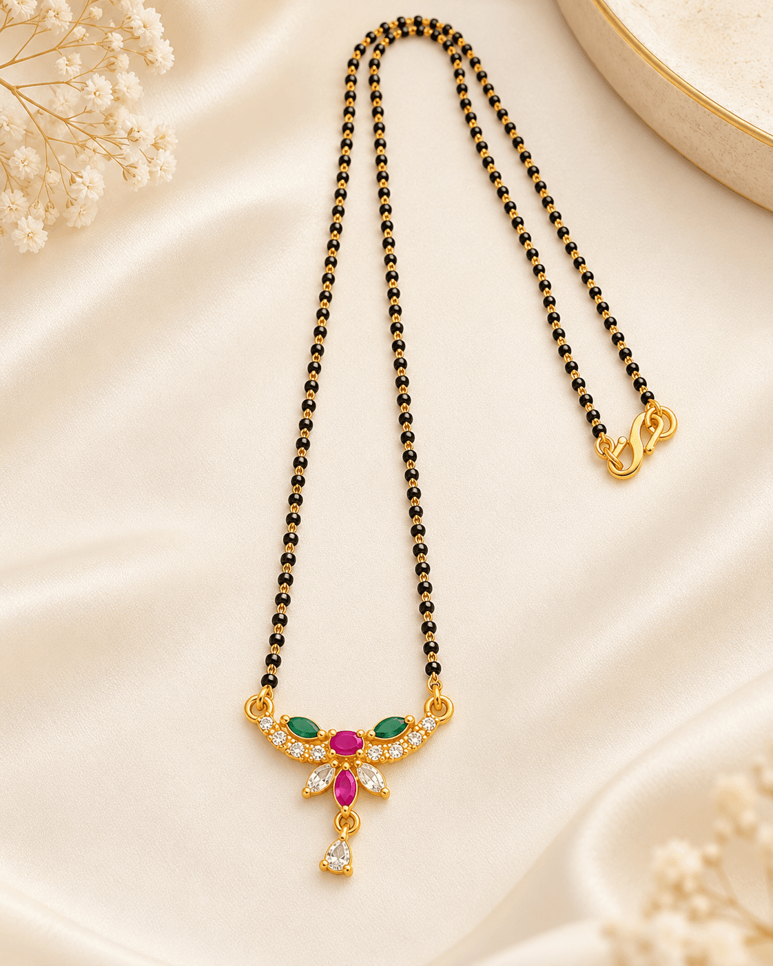 Mangalsutra with twin black bead chain and a gold-colour pendant with green, pink and clear accents