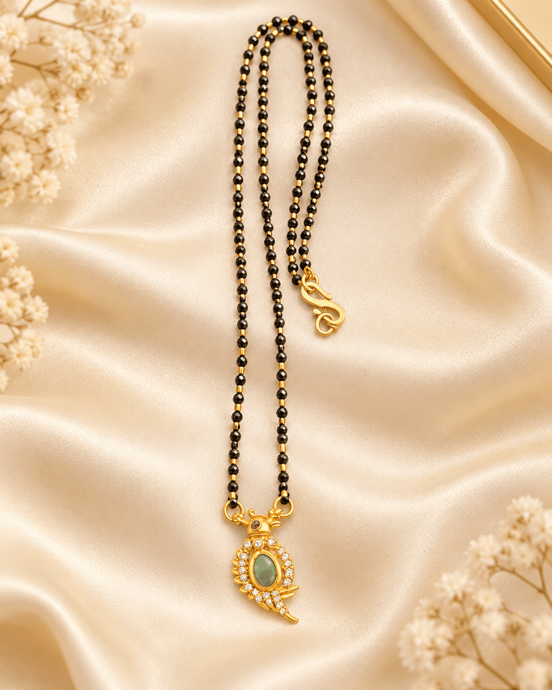 Two-strand black beaded mangalsutra with gold-tone pendant featuring green centre and clear accents