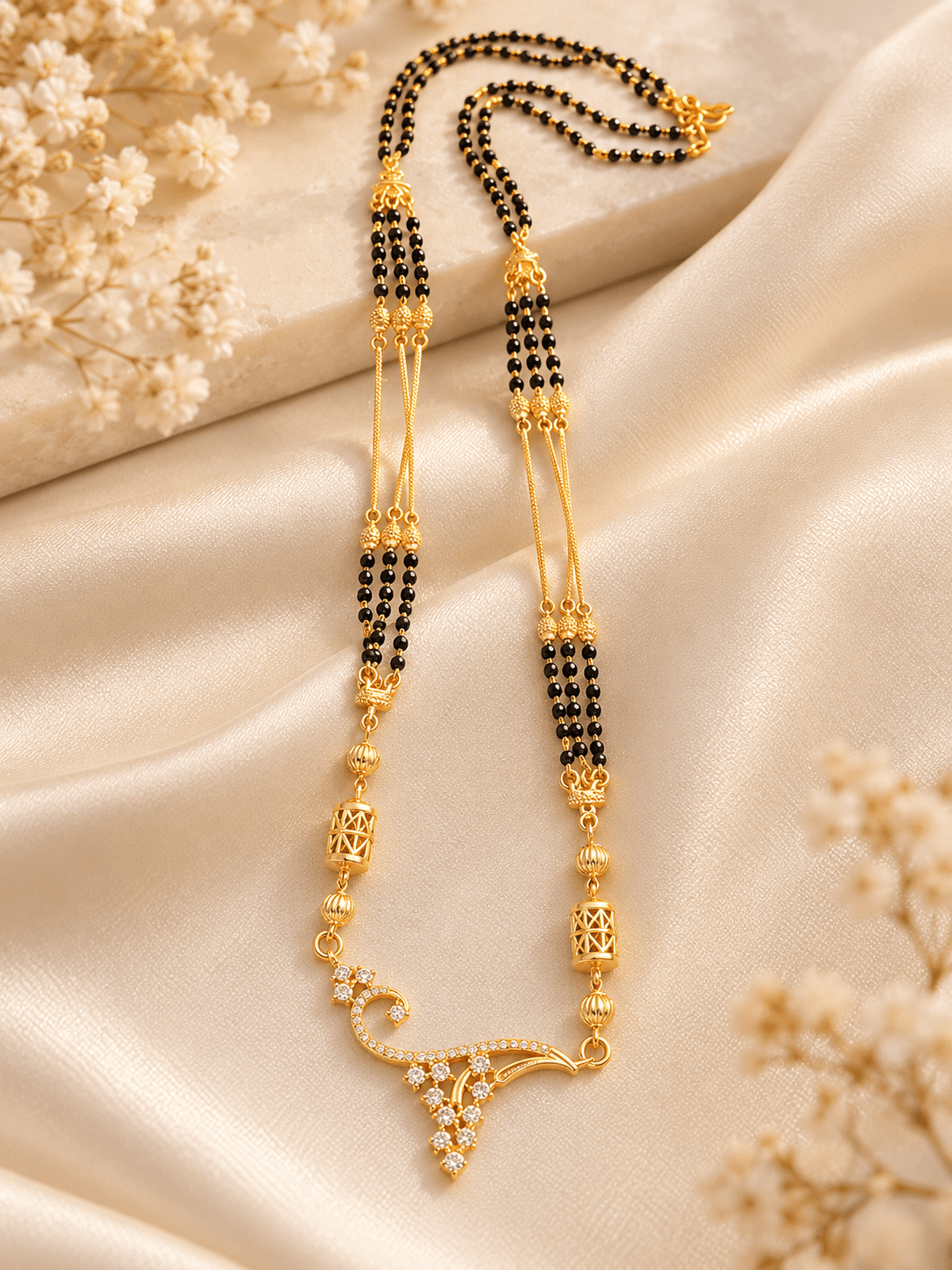 Mangalsutra with triple black bead strands, gold-tone spacers and a curved pendant with clear accents