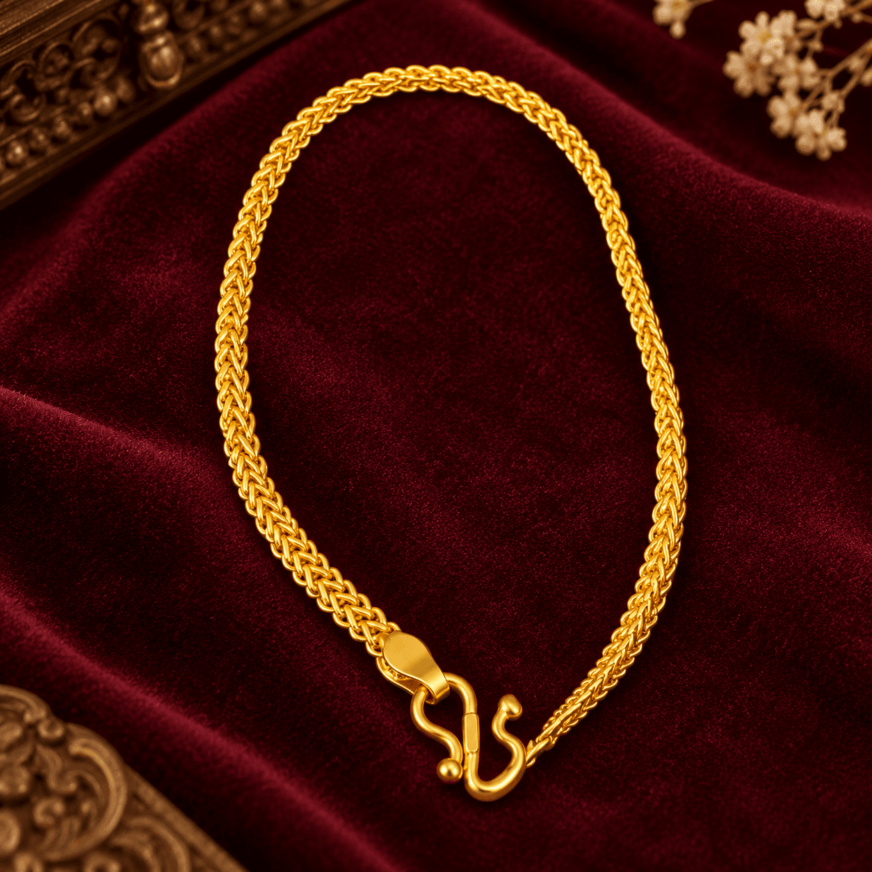 Gold-tone braided link bracelet with hook clasp on velvet background