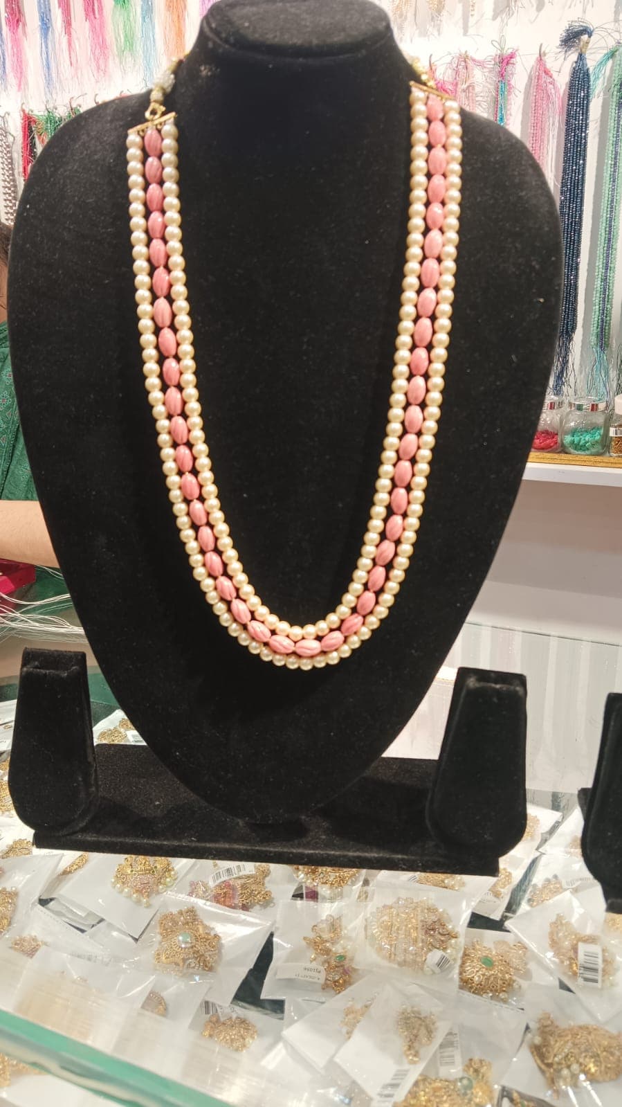 Triple-strand necklace with cream round beads and pink oval beads on display