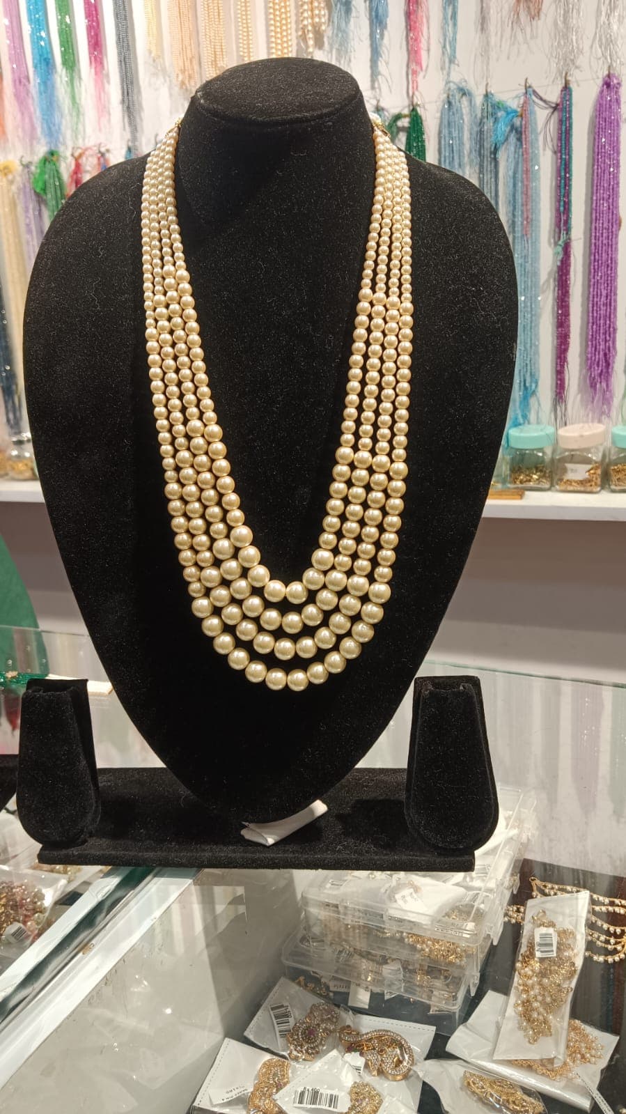 Five-strand necklace of round pearl-coloured beads on a display bust