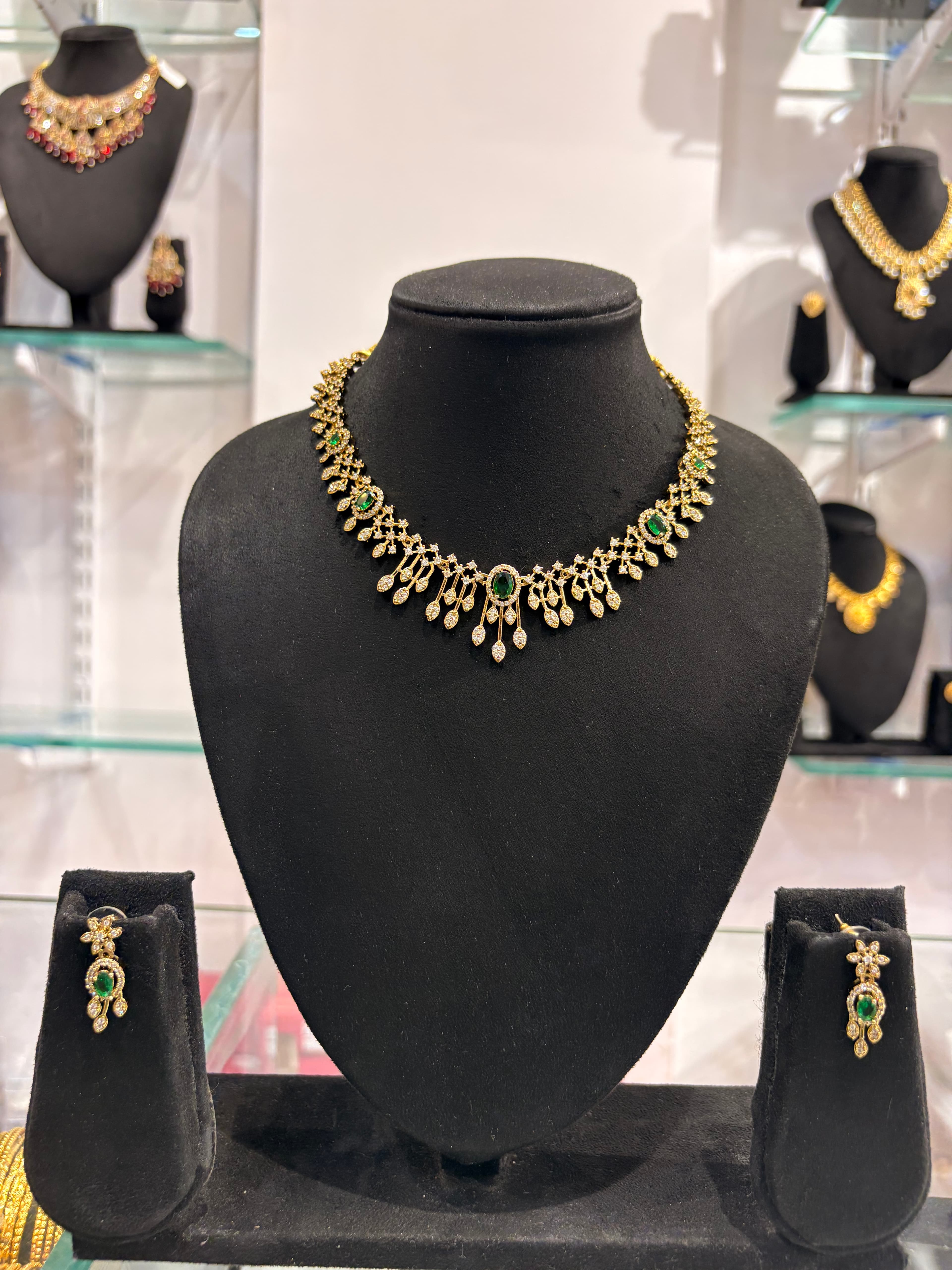 Gold-colour collar necklace with green oval decorative accents and teardrop danglers