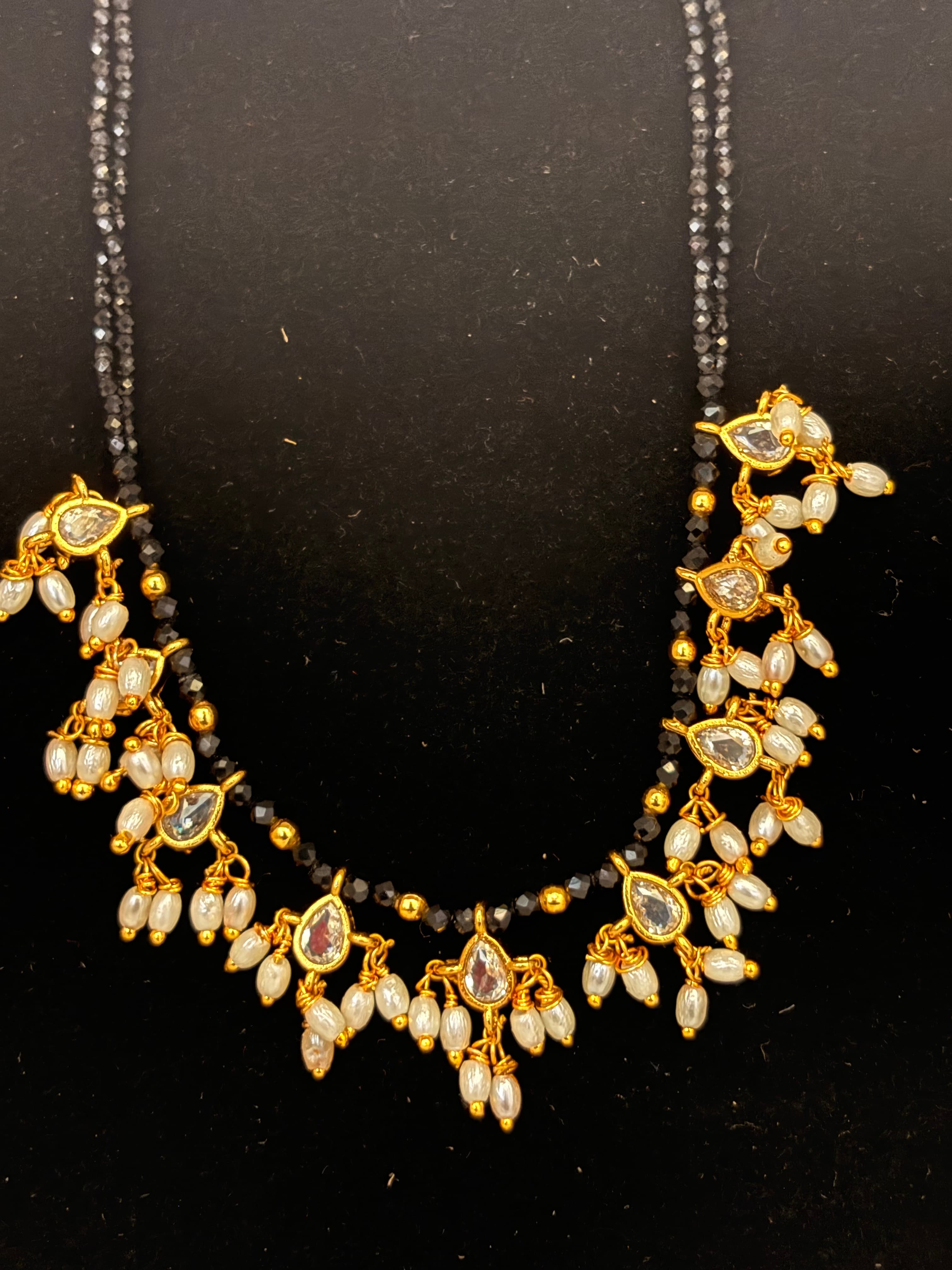 Twin black beaded mangalsutra with gold teardrop charms and clustered white pearl-like dangling beads