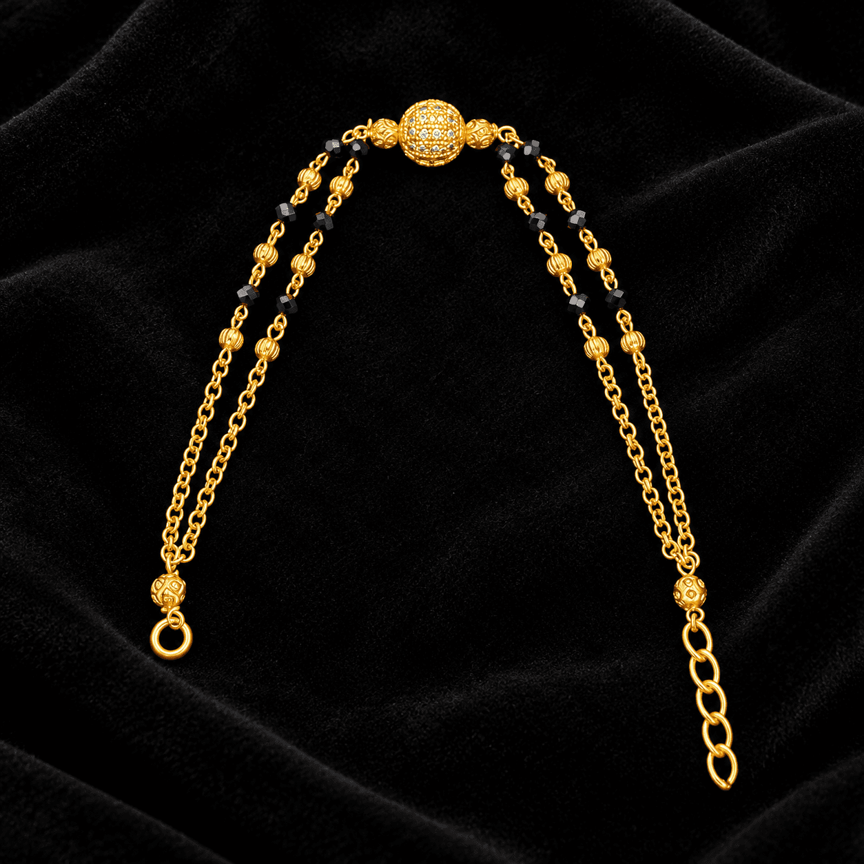Gold-tone double chain bracelet with black bead accents and a textured centre bead